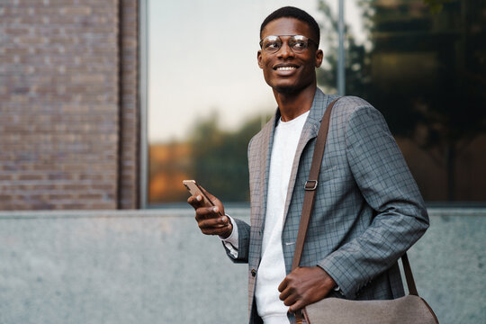 Happy African American Man Using Mobile Phone While Walking On Street