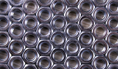 Orderly-laid out metal nuts on a light background
