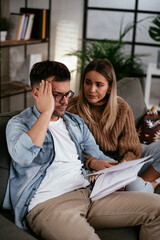 Worried couple paying their bills online with laptop at home in the living room. Couple having financial problems.