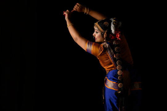 Kuchipudi dancer showing her back while looking sideways and smiling 	