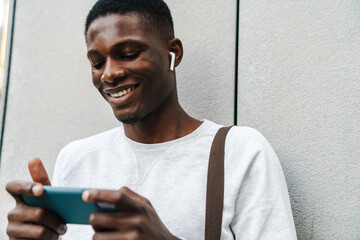 Happy african american man smiling and using mobile phone