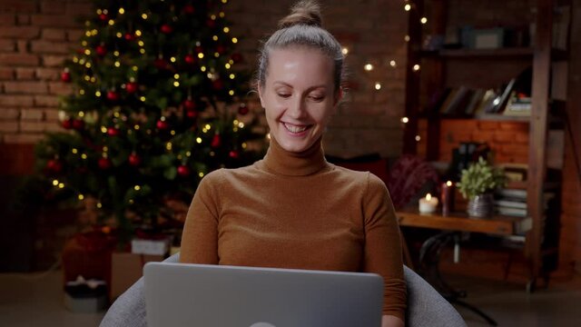 Woman working on laptop computer at home in winter at Christmas. Slow motion video with zoom in.