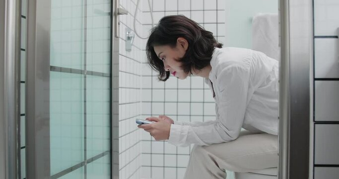 beautiful woman was sitting on the toilet using mobile phone people lifestyle with phone using smartphone all the time in everyday life