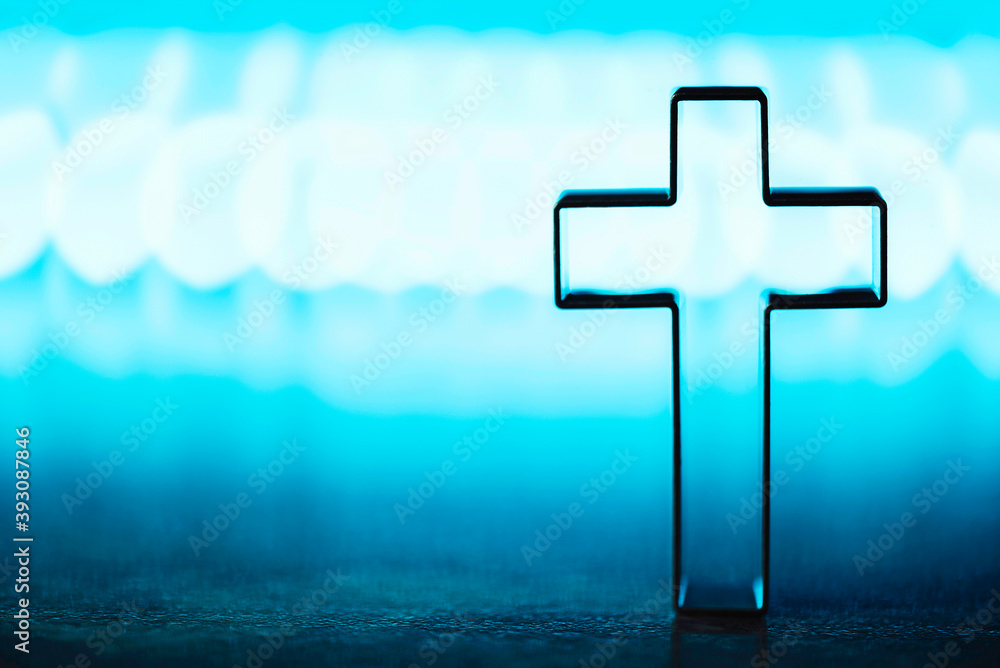 Wall mural Christian cross on blue background with soft bokeh lights background. Copy space. Banner. Church worship, salvation concept. Faith symbol in Jesus Christ. Holy cross for good friday, Easter day