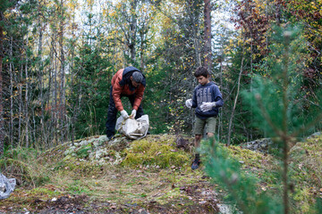 Fototapeta premium big amount of trash in forest, family father and son picking garbage away, global environment issues