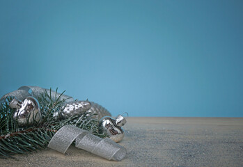 The christmas spruce sprig with silver  decorations on wooden background with blue background