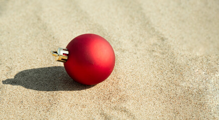 Christmas ornament on the beach, red ball