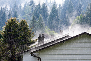 steam comes from the roof houses when the rain falls with sunny light - Powered by Adobe