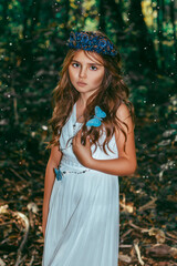 Cute little princess girl with blue butterflies in the forest. Art processing