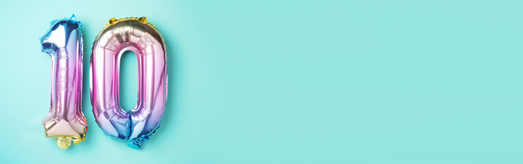 Rainbow foil balloon number, digit ten. Birthday greeting card with inscription 10. Anniversary concept. Top view. Colored numeral on blue background. Numerical digit, Celebration event, template