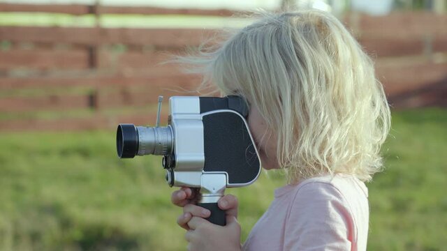 A little girl shoots a video of an old retro camera.