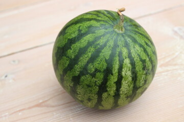 Green striped watermelon on wooden planks background.