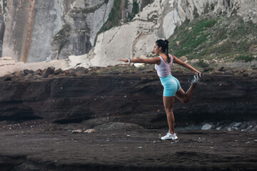 young woman stretching before exercising while looking at the horizon on the beach © Pablo