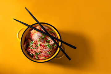 Kimchi cabbage in a bowl with chopsticks on a colored background, top view, Korean cuisine. Trend food photography