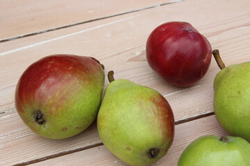 Multi-colored ripe pears and apples on background of boards.