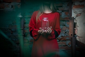 Obraz premium Hands of a girl in a red dress hold a glass jar