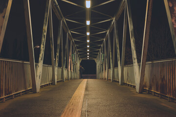 A steel bridge for pedestrians at night, an illuminated pedestrian bridge at night, matt contrast