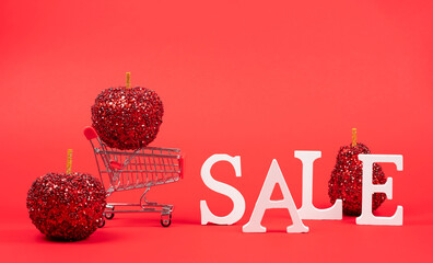 Shopping cart with Christmas decorations standing on a red background. 