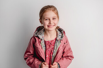 Little girl in pink jacket standing indoors