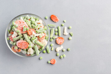 Frozen vegetables in glass bowl and on a table, horizontal, top view, copy space