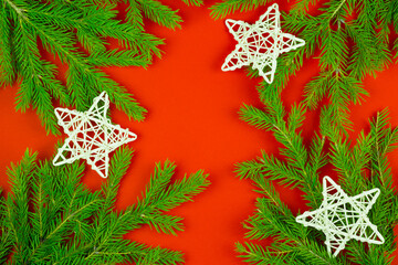  Christmas composition. Spruce branches, white wicker stars on a red background.