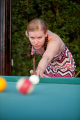 Woman playing pool outdoors, shallow depth of field.