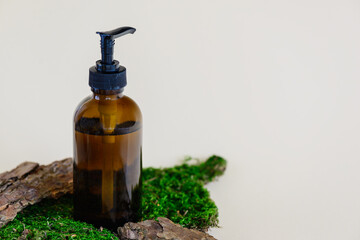 Cosmetic product in a glass bottle on bark and moss. Horizontal orientation, copy space.