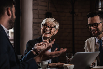 Senior businesswoman holding a meeting with her younger colleagues at office cafeteria.