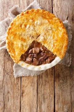 Delicious Traditional English Steak Pie Close-up In A Baking Dish On The Table. Vertical Top View From Above