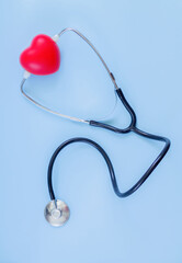 Stethoscope and red heart on blue color background top view