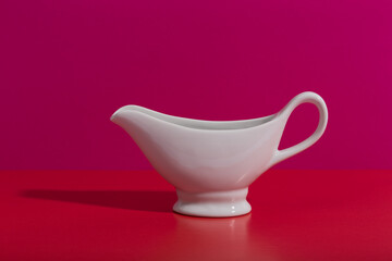 Still life with white ceramic saucer on pink and red background