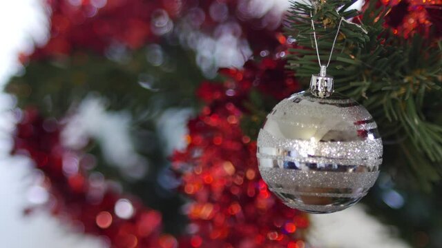 man hands hanging a silver mirror reflective ball on Christmas tree. handsome man wearing mask in reflexion of ball. Merry Christmas and Happy New Year! Celebrating holiday