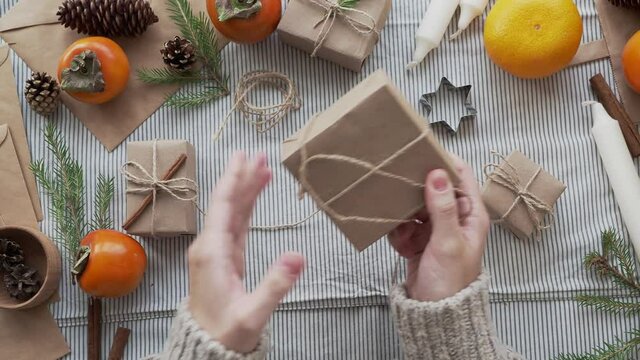 The girl unwraps the gift, unties the bow, close-up. New year's surprise, Christmas atmosphere. Gifts Packed with your own hands. Workshop with Christmas decorations.