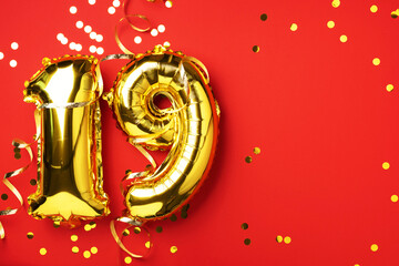 Gold foil balloon number, digit nineteen. Birthday greeting card, inscription 19. Anniversary celebration event. Banner. Stylish golden numeral, bright shiny glitter, red background. Numerical digit