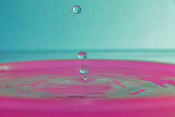 Four drops in suspension with a light colored background and a pink base color