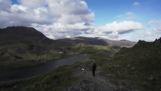 A man walking into the beautiful Welsh countryside with lakes and mountains 
