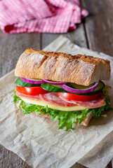 Sandwich with sausage, cheese, green salad, tomatoes, cucumbers and onions. Fast food. Breakfast. Healthy eating.