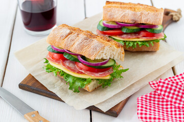 Sandwich with sausage, cheese, green salad, tomatoes, cucumbers and onions. Fast food. Breakfast. Healthy eating.