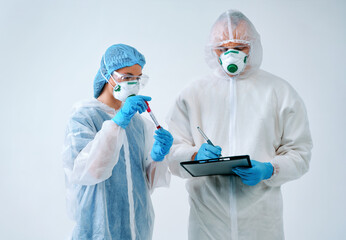 Doctor holds clipboard and nurse shows blood test result. Healthcare workers in protective suits and medical masks