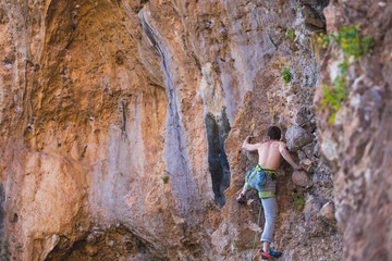 Obraz premium A strong man climbs a beautiful orange rock.