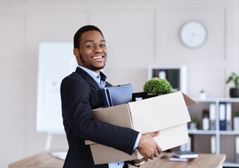 Happy black businessman moving office with box and his belongings