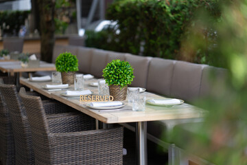 The plaque is reserved on the served table of a summer outdoor cafe or restaurant. Shallow depth of field, blurred background