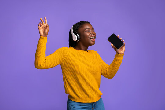 Black Woman Having Fun With Smartphone And Wireless Headphones, Singing And Dancing