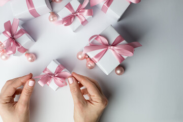 White gift with a red ribbon in female hands.Set of gift box isolated on white background.Christmas gift boxes on white background.Beautiful Christmas background with shiny balls and ribbons in pastel