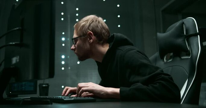 A young man is working at a computer, squinting and leaning closer to see the text on the monitor