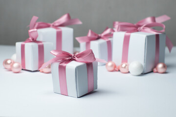 White gifts with pink ribbons. Set of gift box isolated on white background.Christmas gift boxes on white background. Beautiful Christmas background with shiny balls and ribbons in pastel pink color. 