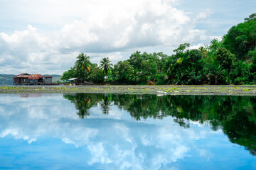 A quiet view of the lake with a reflection of the blue sky on the surface of the water. Beautiful lake landscape photos for backgrounds and wallpapers