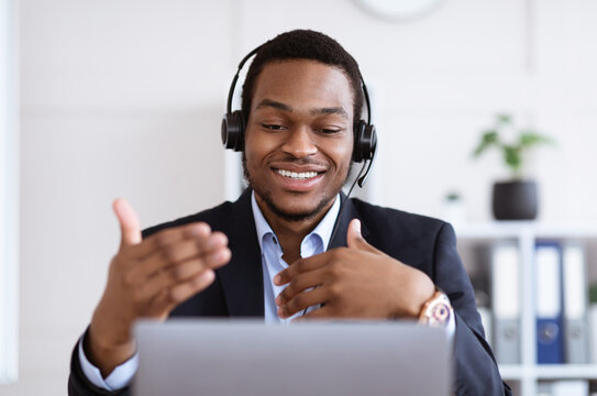 Happy black businessman with headset having online conference