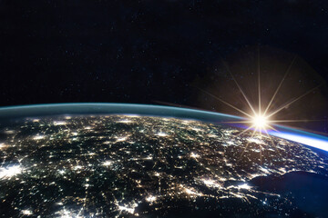 Composite image of the sun rising on earth view from space with the lights of the cities at night....