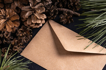 Brown envelope and pine cones on dark vintage table. Letter to santa. New year invitation. 